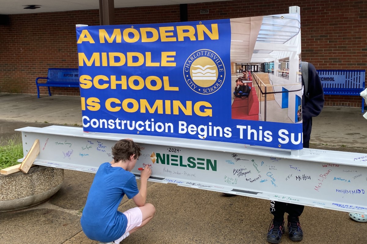 Middle school students and staff sign steel beam for new academic building