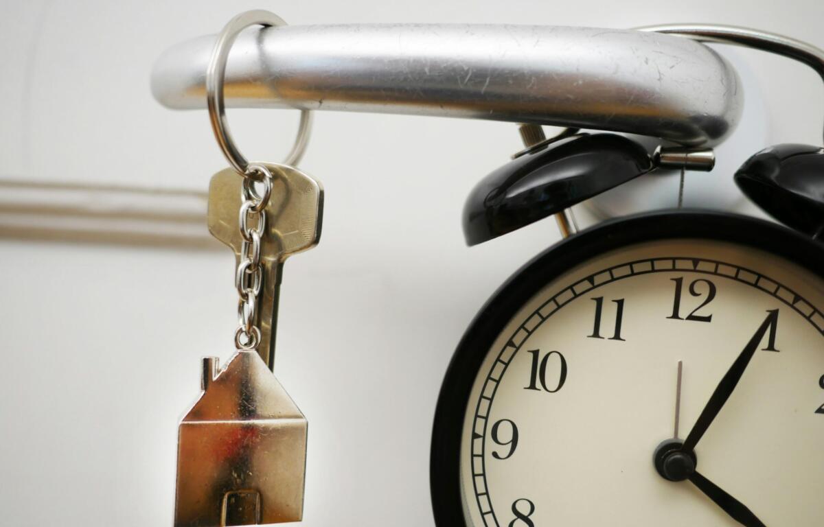 House Key on doorknob with a clock in the lower right hand corner.