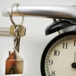 House Key on doorknob with a clock in the lower right hand corner.