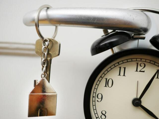 House Key on doorknob with a clock in the lower right hand corner.