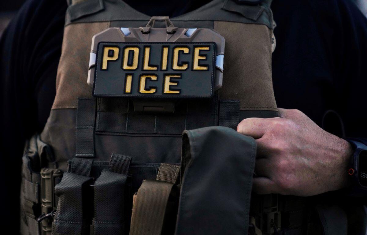 Close-up of a tactical vest with multiple pouches and a badge that reads POLICE ICE.