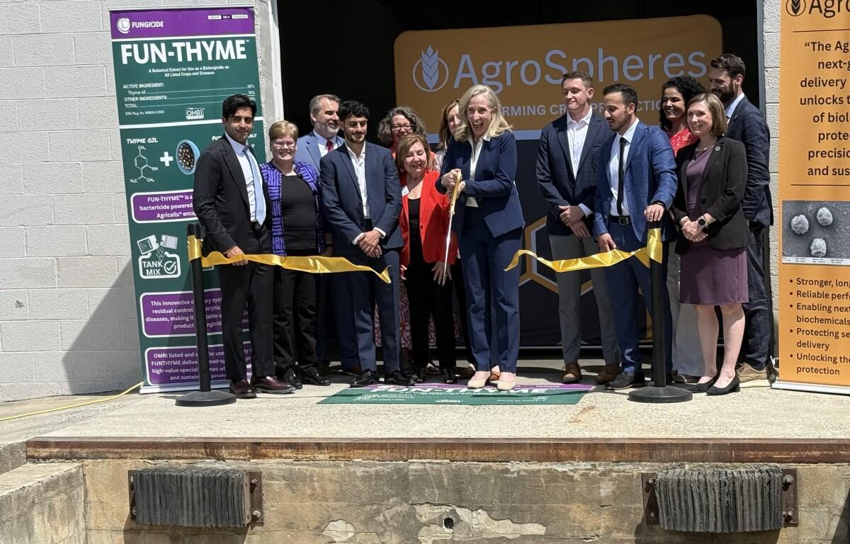 Group of people cutting a yellow ribbon at AgroSpheres launch, with banners on the sides.