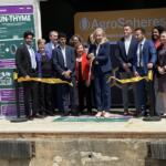 Group of people cutting a yellow ribbon at AgroSpheres launch, with banners on the sides.