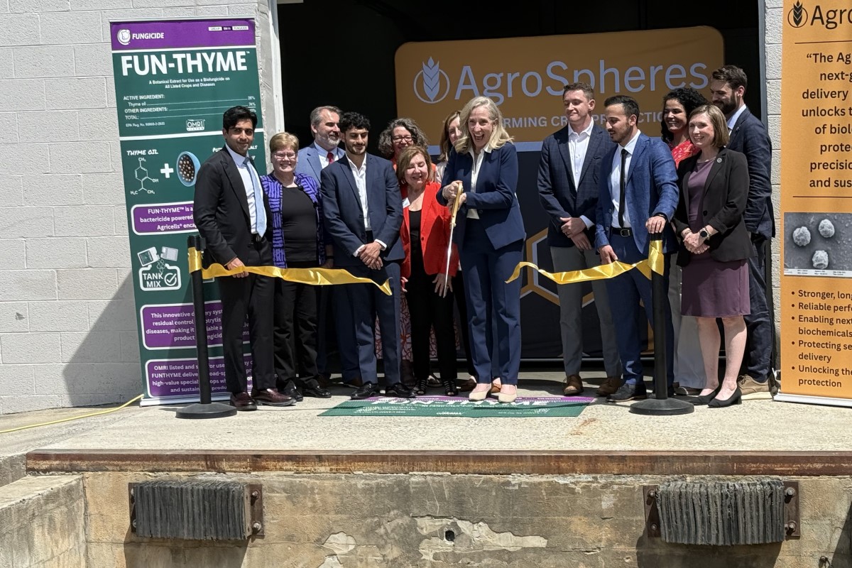 Group of people cutting a yellow ribbon at AgroSpheres launch, with banners on the sides.