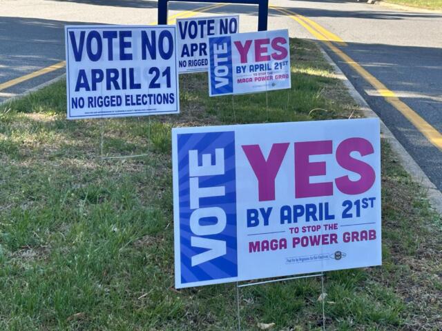 Campaign signs on a grassy roadside urging votes for April 21, some say 'Vote No' and others 'Yes' in bold letters.