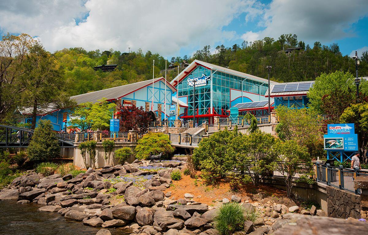 Ripley's Aquarium exterior with glass facade and red/blue accents along a rocky shoreline and boardwalk.
