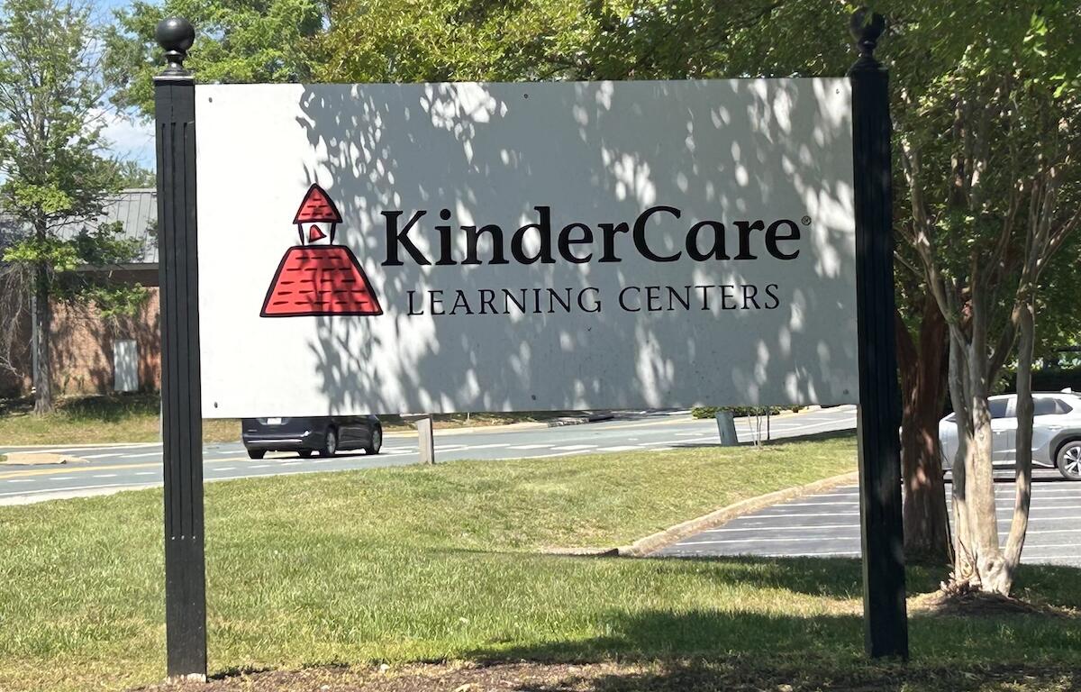 Outdoor KinderCare Learning Centers sign with red logo, mounted on tall black posts.