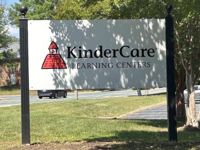 Outdoor KinderCare Learning Centers sign with red logo, mounted on tall black posts.