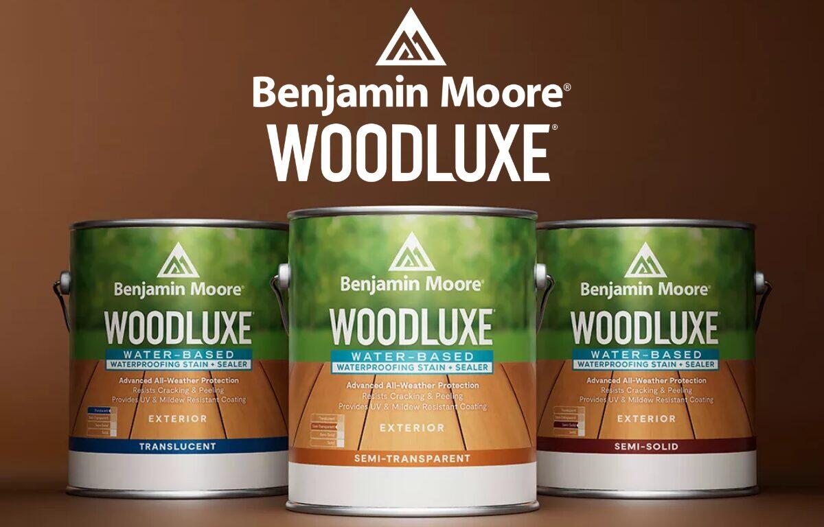 Three Benjamin Moore WoodLuxe paint cans in front of a brown backdrop, with a white WoodLuxe logo on top.