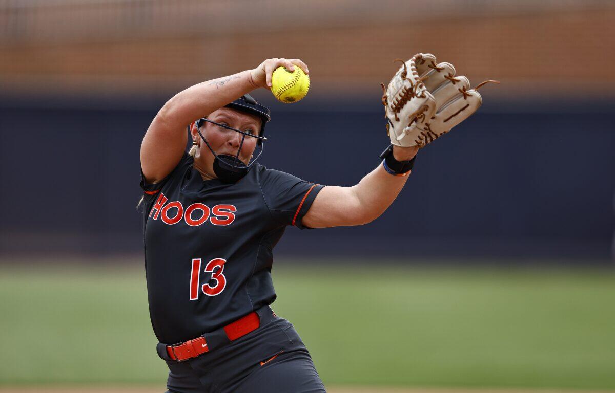 Softball pitcher in black uniform labeled HOOS, number 13, throws a yellow ball with glove raised mid-throw on a field.