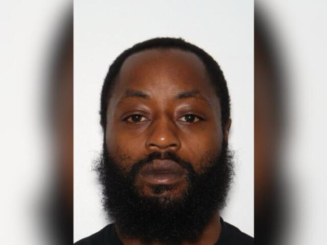 Portrait of a man with a full beard and short hair, facing the camera against a plain light background, neutral expression.