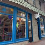 Front of the Discovery Museum with bright blue window frames and colorful star shapes on the glass; ducts and tubes visible inside.ans