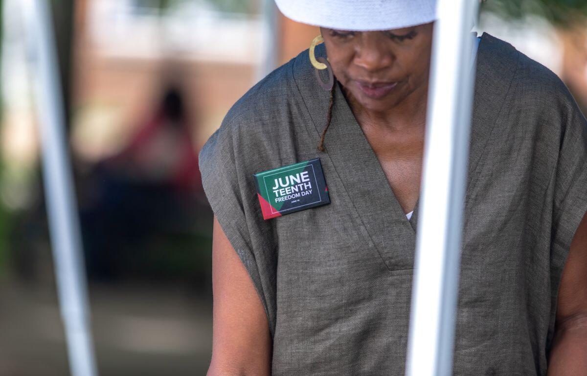 Person wearing a gray sleeveless top with a badge reading 'June Teenth Freedom Day' pinned to the chest.