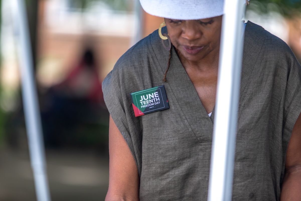 Person wearing a gray sleeveless top with a badge reading 'June Teenth Freedom Day' pinned to the chest.