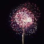 Firework bursting in a dark night sky with red, white, and blue sparks around a bright center.