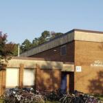 Brick elementary school building with a row of bicycles parked outside on a sunny day.