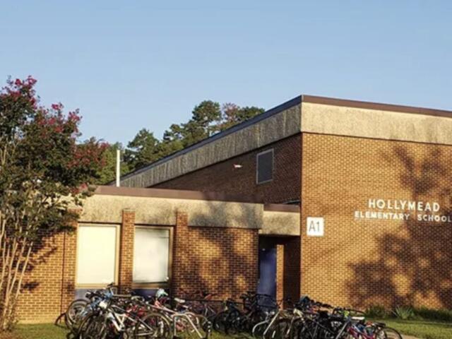 Brick elementary school building with a row of bicycles parked outside on a sunny day.