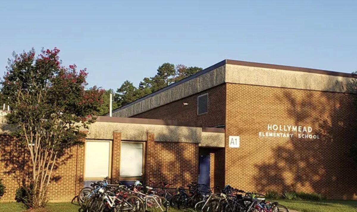 Brick elementary school building with a row of bicycles parked outside on a sunny day.