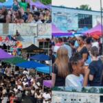 Crowd gathers at an outdoor festival with colorful tents and a mural backdrop in the background.