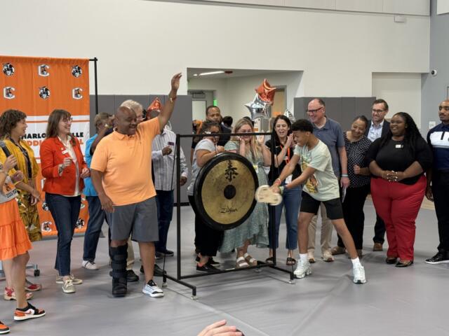 Devin Coles bangs the opening gong with city and school leaders looking on
