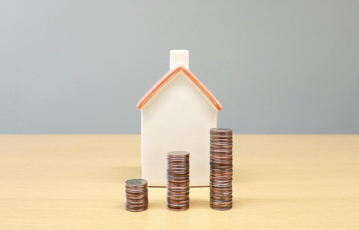 stacks of coins getting higher in front of a model house