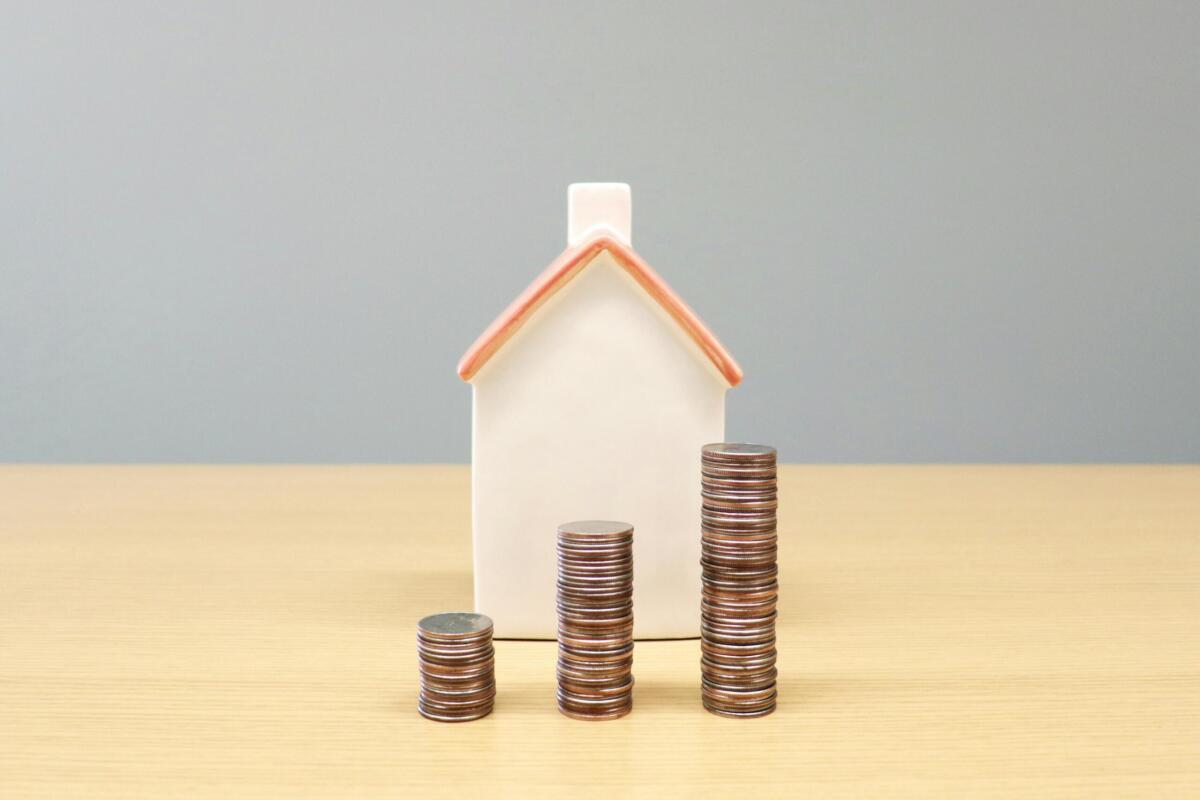 stacks of coins getting higher in front of a model house