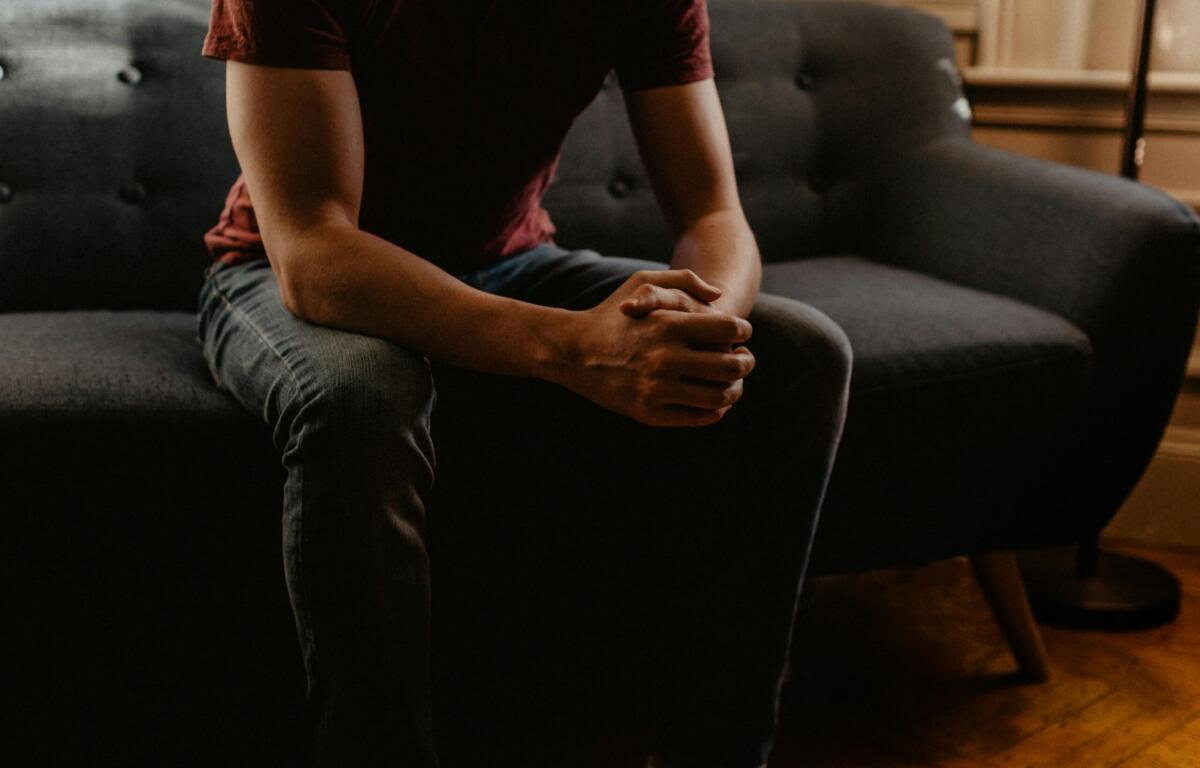 person sitting on couch with hands folded