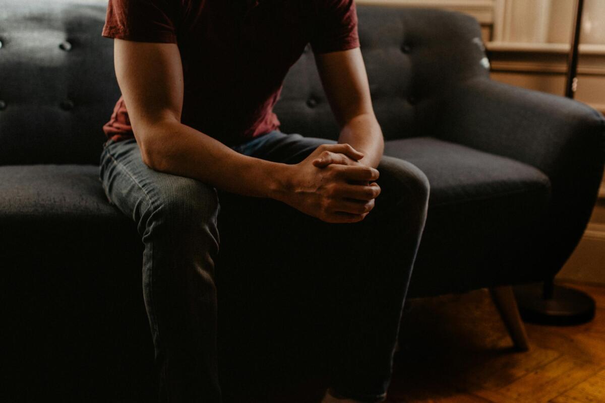 person sitting on couch with hands folded