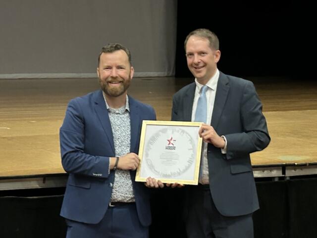 Director of Bands Jason Hackworth (left) accepts the official invitation to the parade from Deputy Lieutenant for Greater London Steve Summers (right).