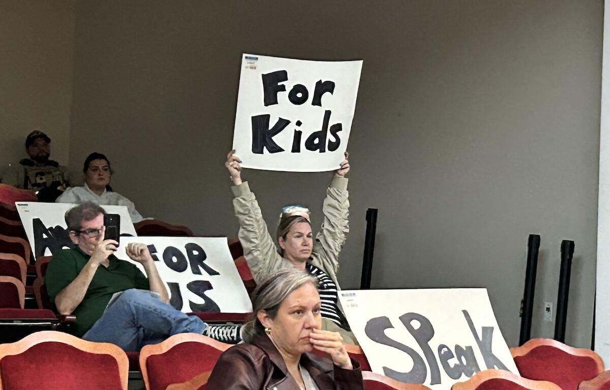 Daisy Rojas holds up a sign during an Albemarle County School Board meeting