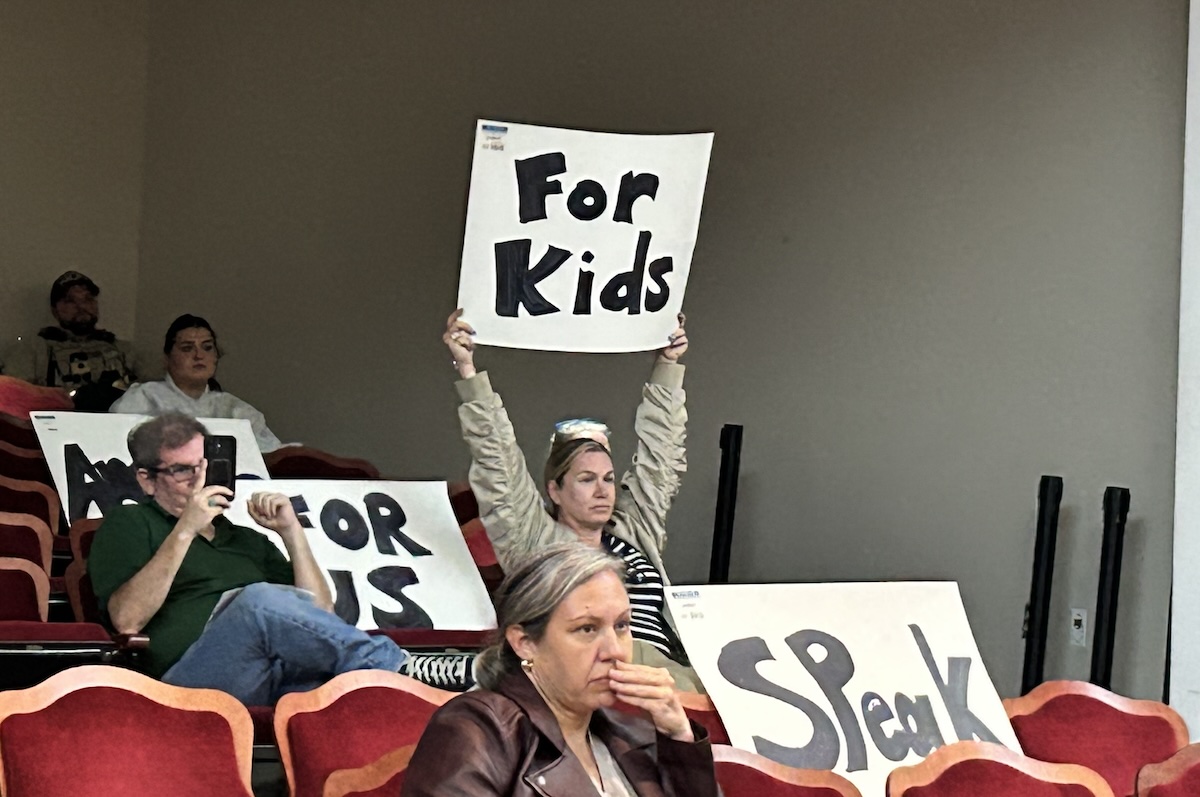 Daisy Rojas holds up a sign during an Albemarle County School Board meeting